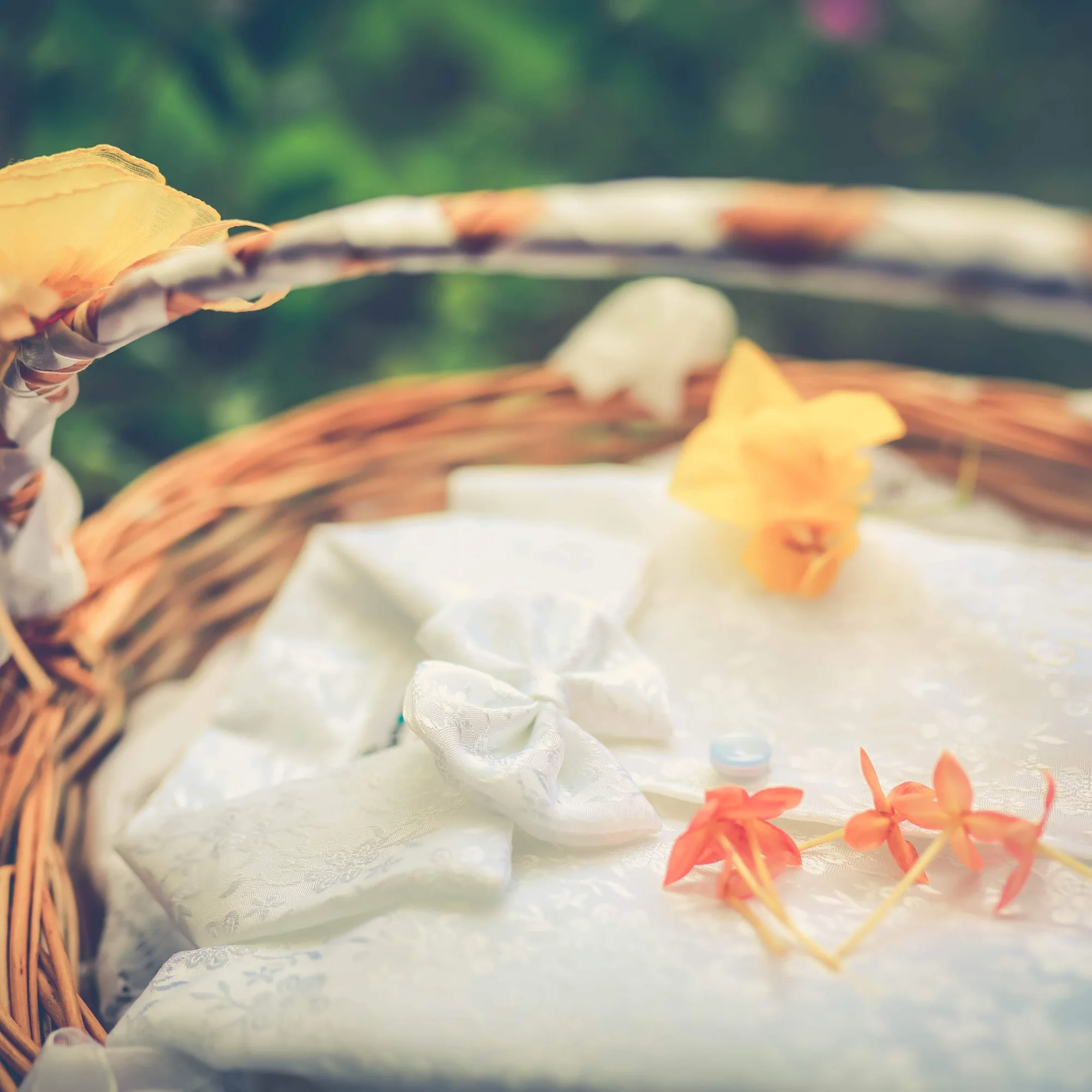 A woven basket of white silk-wrapped bundles and soft flowers